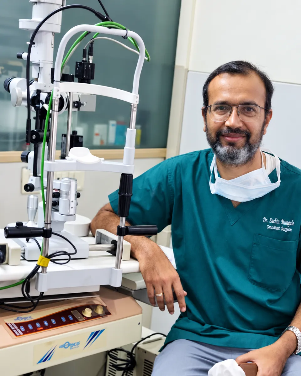 Dr. Sachin Mungale seated beside a slit lamp examination unit.